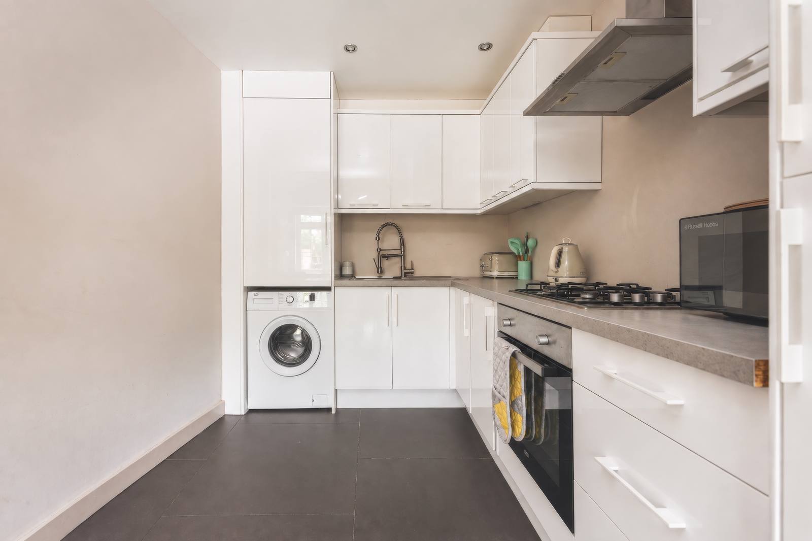 White kitchen with oven, gas hob, microwave and washing machine